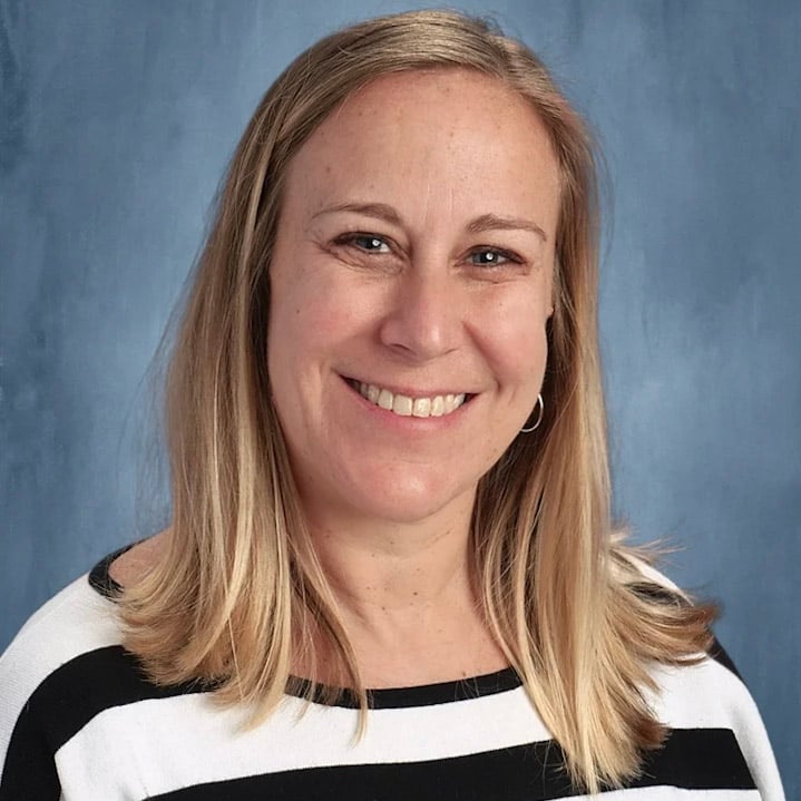 Woman smiling with a blue background and a black and white striped shirt 